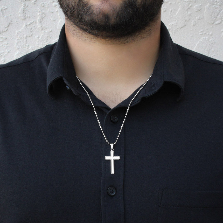 Silver cross pendant on ball-chain necklace worn with dark shirt