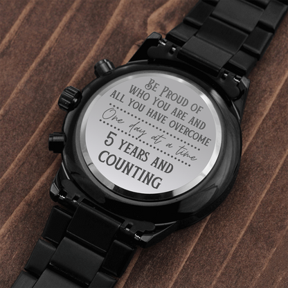 Black chronograph watch caseback close-up with engraved inspirational message