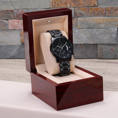 Black chronograph watch in open maroon wooden gift box with metal link bracelet