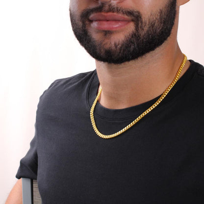 Gold Cuban link chain necklace worn by a man, close-up on the neckline