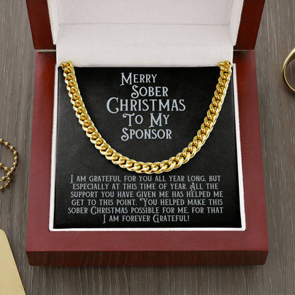 Gold-tone Cuban link chain necklace close-up with message card reading “Merry Sober Christmas to My Sponsor”.