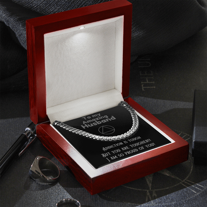 Silver Cuban link chain necklace resting in gift box with black card and text
