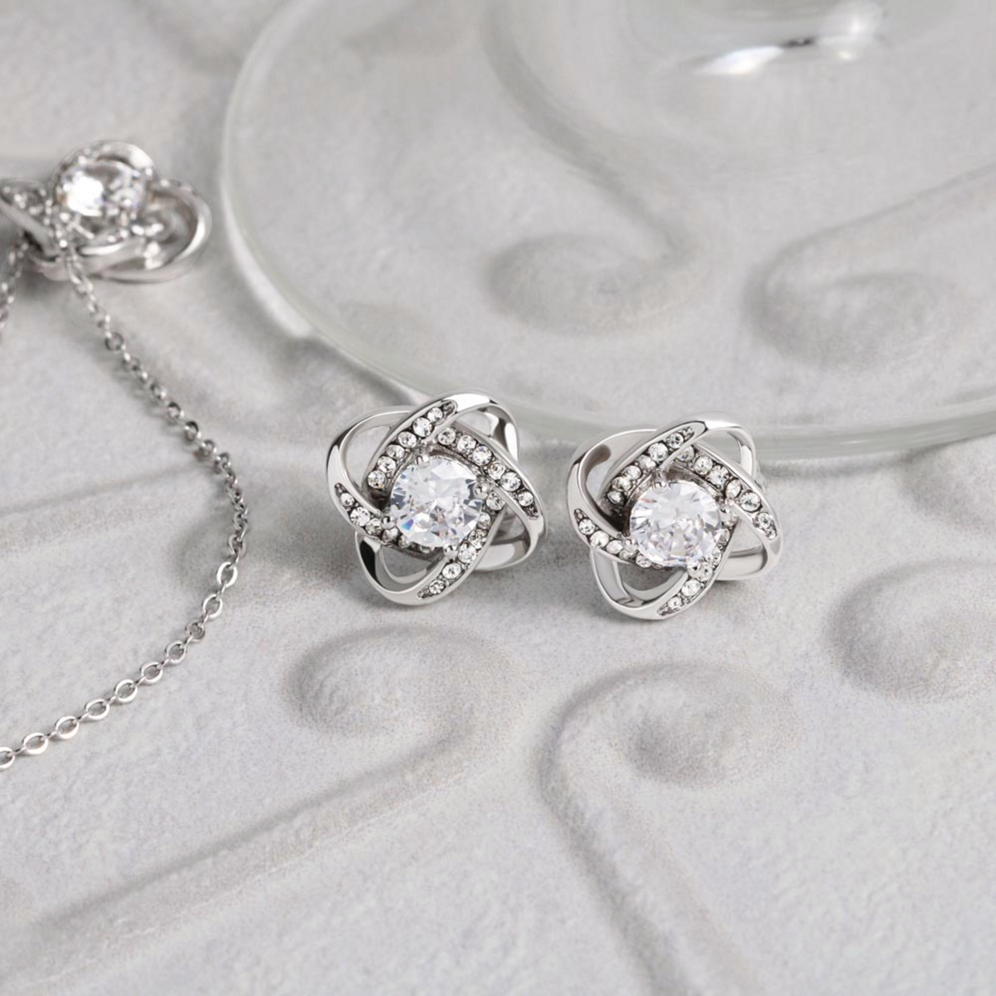 Silver-tone cubic zirconia knot stud earrings, round center stone with halo detail