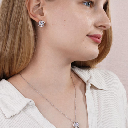 Silver-tone cubic zirconia knot stud earrings on ear, round center stone with halo